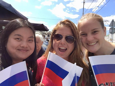 Students on the 2015 UGA Study Abroad program in Russia at a market, holding Russian flags