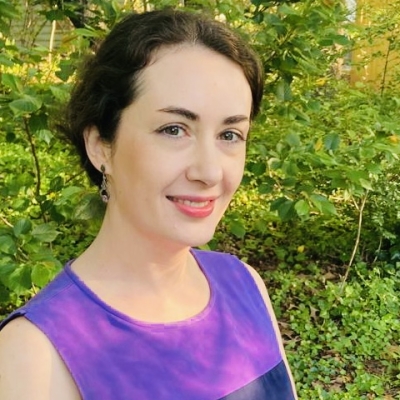 Dr. Alexandra Shapiro, smiling and standing in front of greenery.