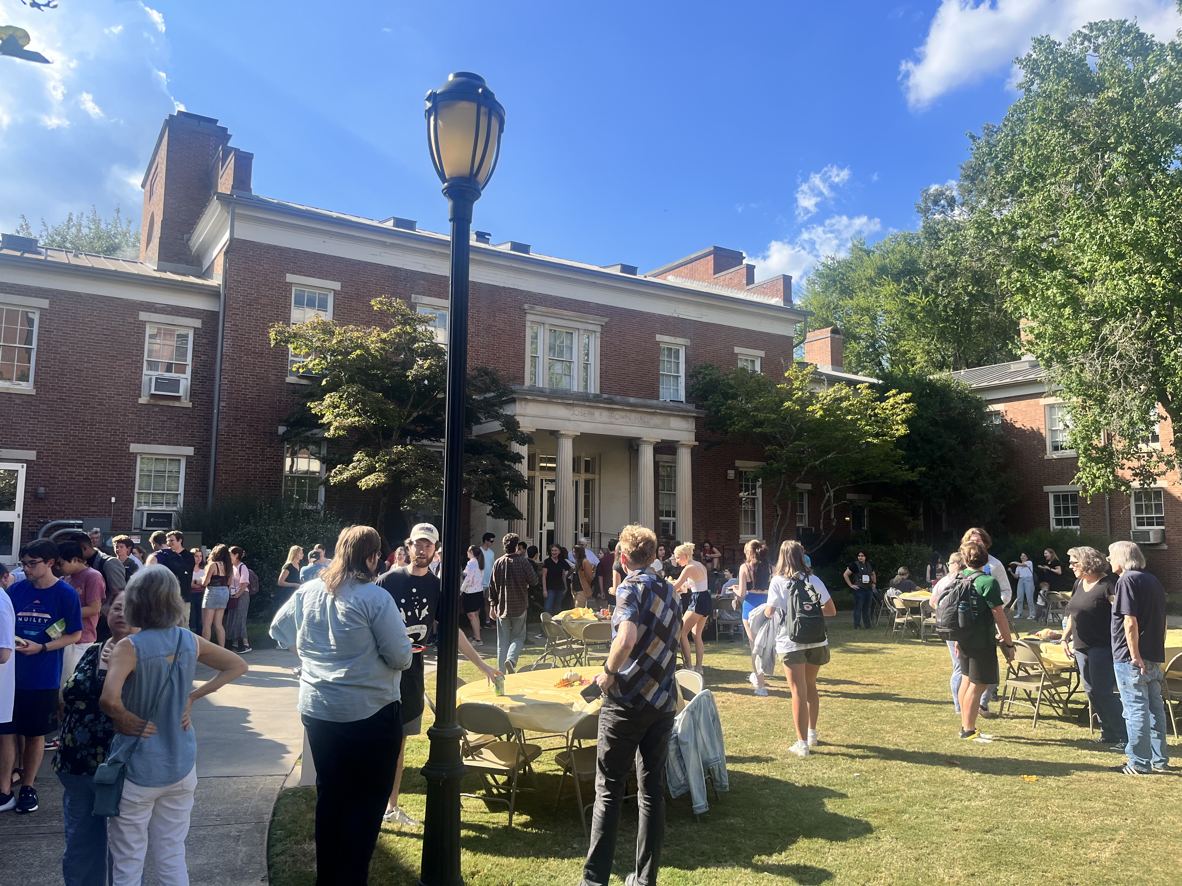 Fall Social 2023. People are in a sunny courtyard talking together and eating. 